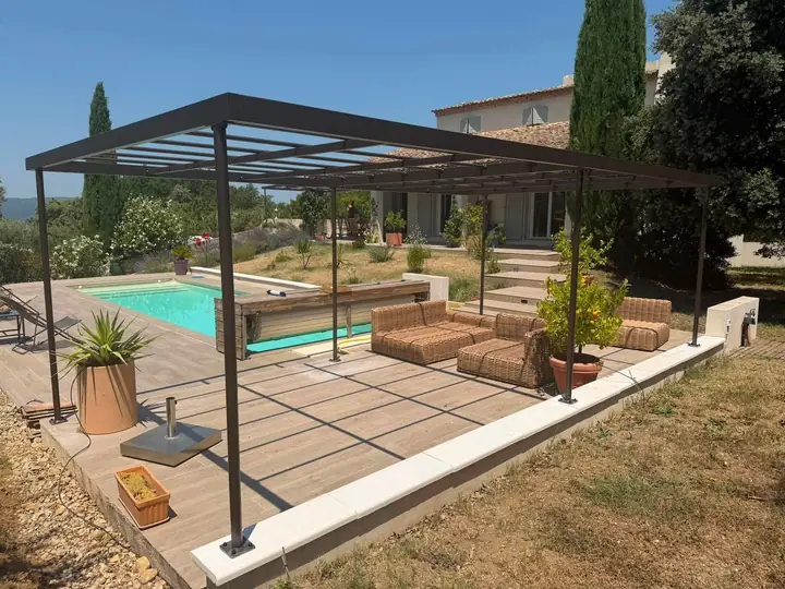 Pergola bioclimatique à lames orientables au bord d'une piscine, fabriquée par TS'METAL à Anneyron